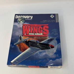 Puede incluir: Una caja rectangular de juego de computadora Discovery Channel Wings Over Europe con un fondo de cielo azul oscuro con nubes, un título central rojo y un gráfico de un avión de hélice plateado y negro volando hacia el espectador.