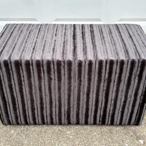 May include: A gray striped upholstered ottoman with a rectangular shape.