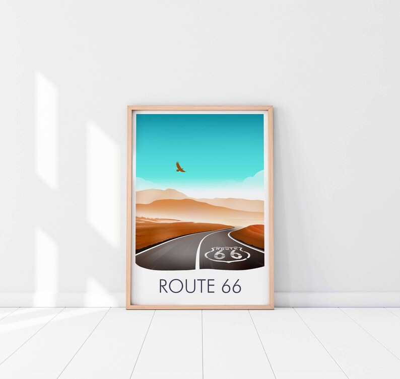 May include: A framed print of a desert landscape with a road leading to a Route 66 sign. The sky is blue and there is a bird flying in the distance. The text "ROUTE 66" is printed below the image.