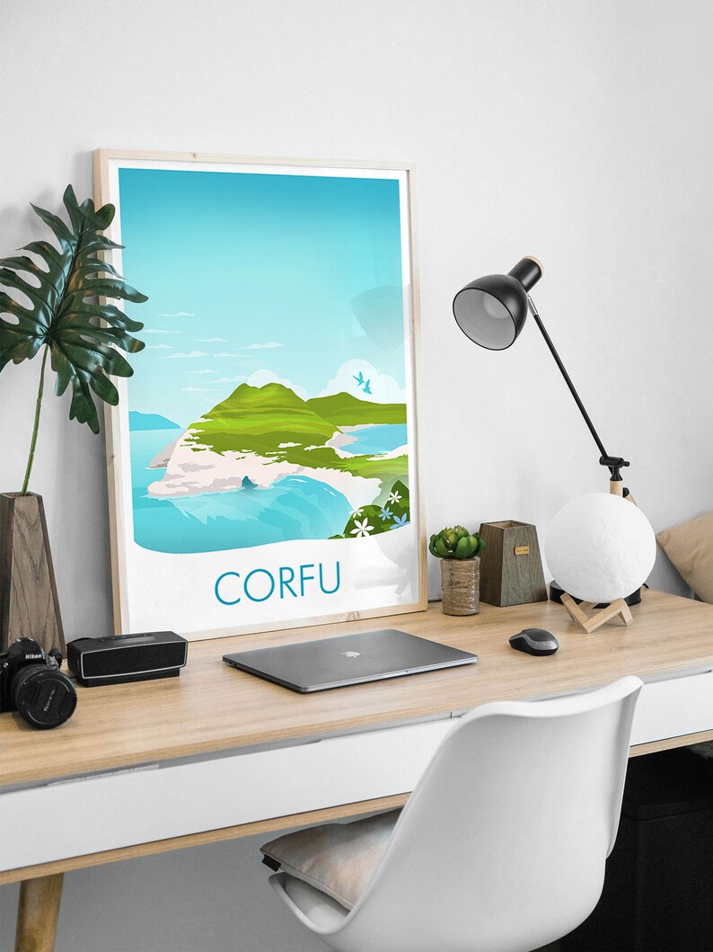 May include: A framed travel poster with the word "CORFU" in blue, depicting a scenic view of the island with green hills, blue water, and a bright sky. The poster is on a wooden desk with a laptop, lamp, and decorative items.