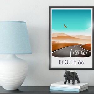 May include: A framed print of a desert landscape with a road leading to a Route 66 sign. The sky is blue with a single bird flying overhead. The text "ROUTE 66" is printed below the image.