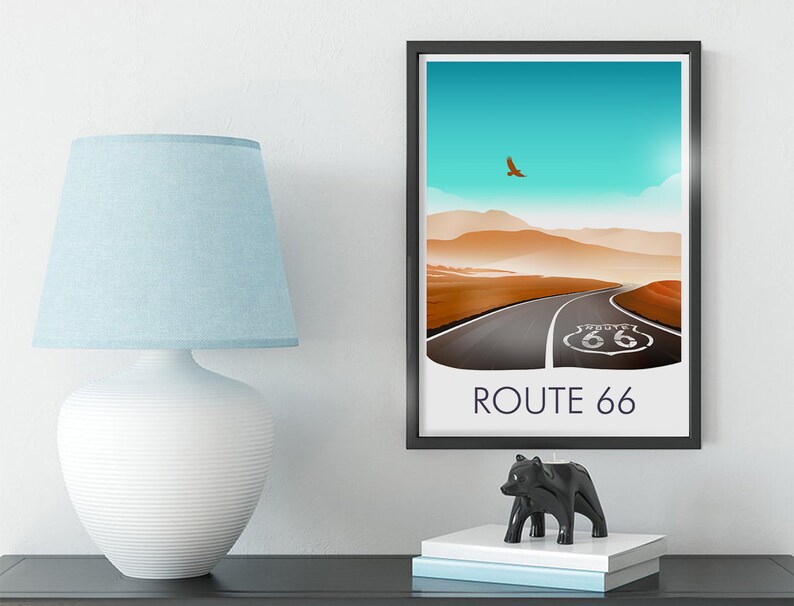 May include: A framed print of a desert landscape with a road leading to a Route 66 sign. The sky is blue with a single bird flying overhead. The text "ROUTE 66" is printed below the image.
