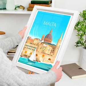 May include: A framed illustration of the city of Valletta, Malta. The illustration features a blue sky, a sailboat, and the iconic St. John's Co-Cathedral. The text "MALTA VALLETTA" is printed in white at the top of the illustration.
