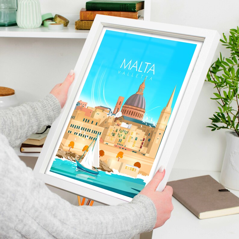 May include: A framed illustration of the city of Valletta, Malta. The illustration features a blue sky, a sailboat, and the iconic St. John's Co-Cathedral. The text "MALTA VALLETTA" is printed in white at the top of the illustration.