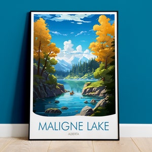 Op de afbeelding: Een ingelijste kunstdruk van Maligne Lake in Alberta, Canada. Het landschap toont een serene meer omgeven door bergen, bomen met gele bladeren en een blauwe lucht met wolken. De print bevat de tekst "MALIGNE LAKE" en "ALBERTA".
