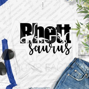 May include: A white t-shirt with a black graphic design that says "Rhett Saurus" with dinosaur silhouettes inside the letters.