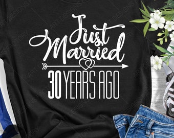May include: Black t-shirt with white text that reads "Just Married 30 Years Ago" with an arrow pointing to the right and two hearts above the text.
