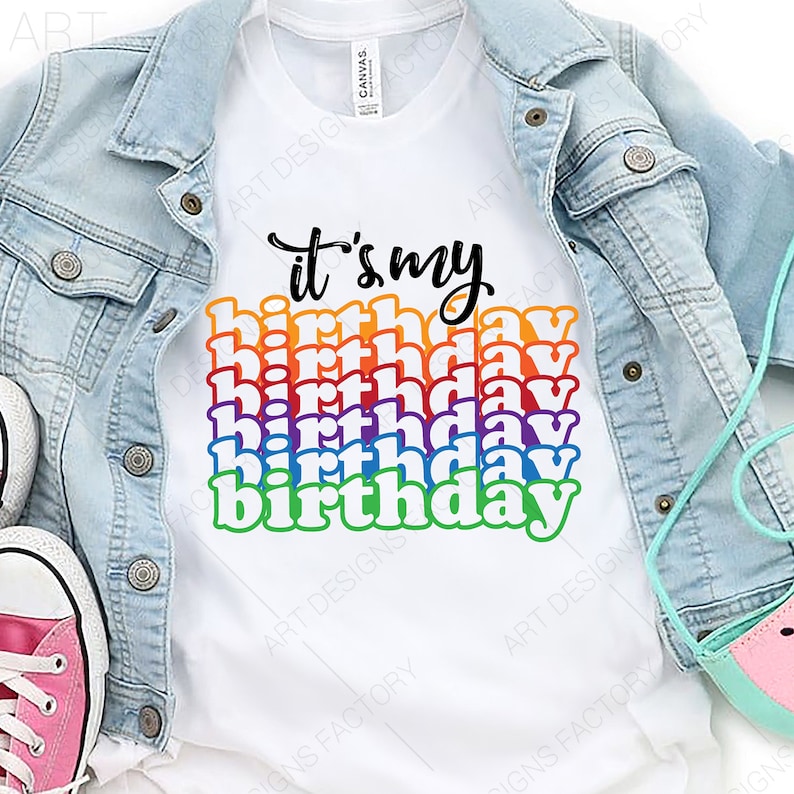 May include: White t-shirt with the text "it's my birthday" in rainbow colors. The text is stacked and the letters are in a retro font.