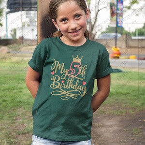 May include: A green t-shirt with a gold crown and the text "My 5th Birthday" in gold lettering with pink hearts.