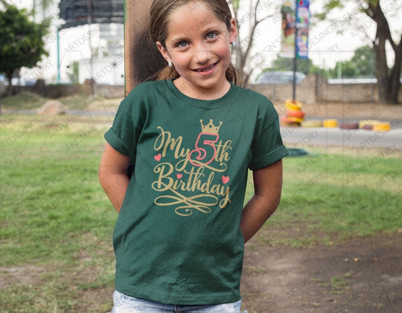 May include: A green t-shirt with a gold crown and the text "My 5th Birthday" in gold lettering with pink hearts.