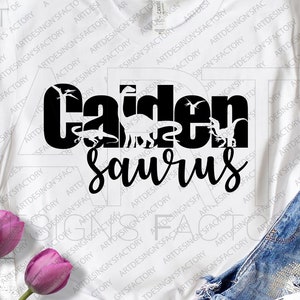 Peut inclure: Un t-shirt blanc avec du texte noir qui dit "Carden Saurus" avec une silhouette de dinosaures derrière le texte.