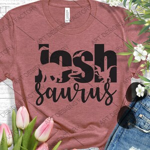 May include: A maroon t-shirt with the text "Joshsaurus" in black. The text is made up of dinosaur silhouettes.