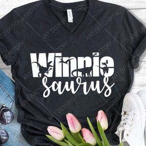 May include: A black t-shirt with a white graphic that says "Winnie Saurus" with dinosaur silhouettes. The graphic is centred on the shirt.