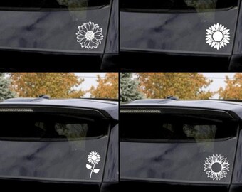 Peut inclure: Quatre autocollants en vinyle blanc en forme de tournesol sur une vitre de voiture noire. Les autocollants sont de styles différents, notamment un tournesol simple, un tournesol avec une tige et un tournesol avec un design plus détaillé.