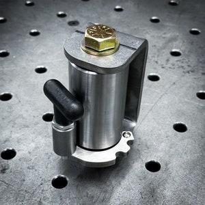 Pode incluir: Uma braçadeira de metal prateada com uma alça preta e uma maçaneta prateada. A braçadeira tem um furo roscado e uma superfície plana. A braçadeira é projetada para ser usada para trabalhos de madeira ou outros projetos de bricolage.