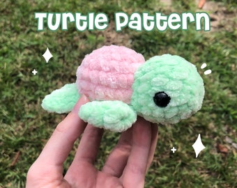 May include: A crocheted turtle toy with a pink shell and green limbs. The turtle has black eyes and a cute expression.