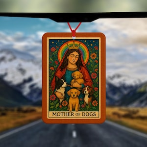 Może przedstawiać: Prostokątny odświeżacz powietrza do samochodu z ilustracją ukoronowanej kobiety, psów, kwiatów i tęczy, z napisem "MOTHER OF DOGS". Odświeżacz powietrza wisi na czerwonym sznurku, na tle gór i drogi.