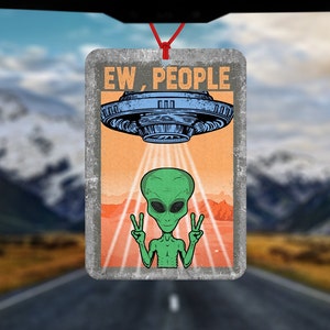Può includere: Deodorante per ambienti rettangolare con un design retrò con un alieno verde che fa il segno della pace sotto un UFO blu. Il testo "EW, PEOPLE" è sopra l'UFO. Il deodorante per ambienti è appeso con uno spago rosso.