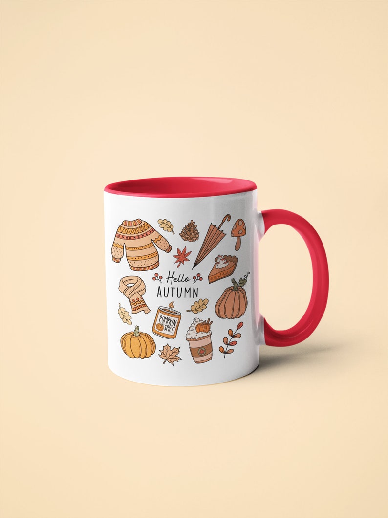 May include: White ceramic mug with a red interior and handle, decorated with autumn-themed illustrations. The design includes a sweater, leaves, pumpkins, and the text "Hello Autumn".
