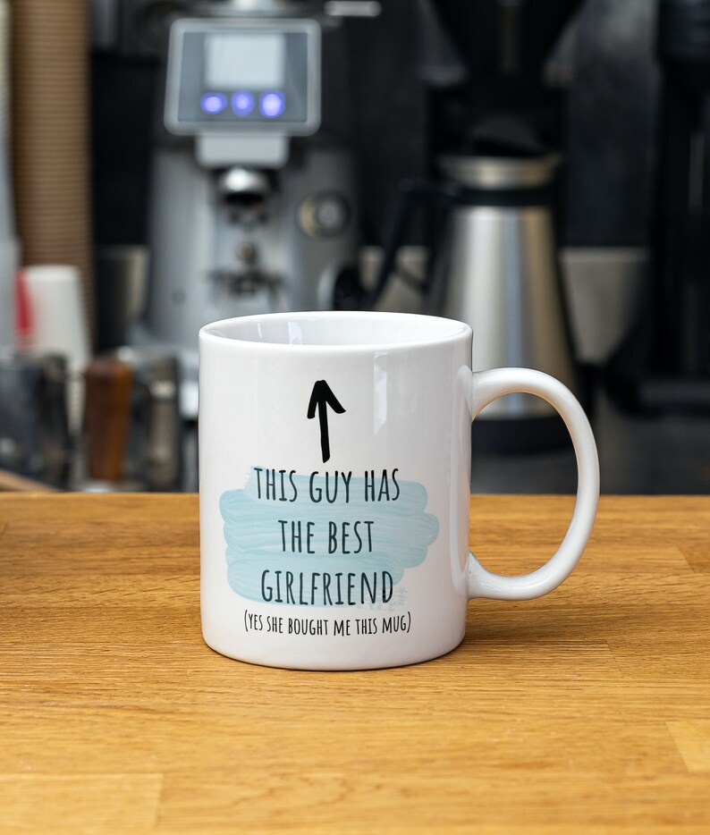 Pode incluir: Caneca de cer&acirc;mica branca com uma seta preta apontando para cima e o texto "Este cara tem a melhor namorada (sim, ela me comprou esta caneca)".