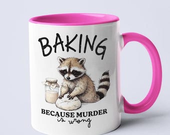 Pode incluir: Caneca de cerâmica branca com borda e alça rosa. A caneca apresenta uma ilustração em preto e branco de um guaxinim assando com o texto "Baking because murder is wrong".