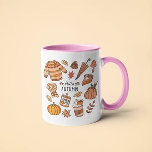 May include: White ceramic mug with a pink interior and handle, decorated with autumn-themed illustrations. The design includes a sweater, leaves, pumpkins, and the text "Hello Autumn".