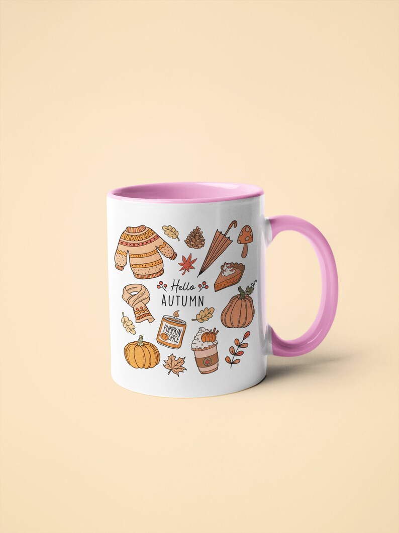 May include: White ceramic mug with a pink interior and handle, decorated with autumn-themed illustrations. The design includes a sweater, leaves, pumpkins, and the text "Hello Autumn".