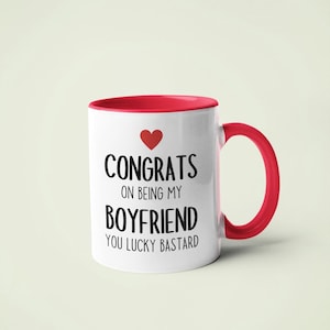 A white and red mug with text that reads "CONGRATS ON BEING MY BOYFRIEND YOU LUCKY BASTARD" printed on it.
