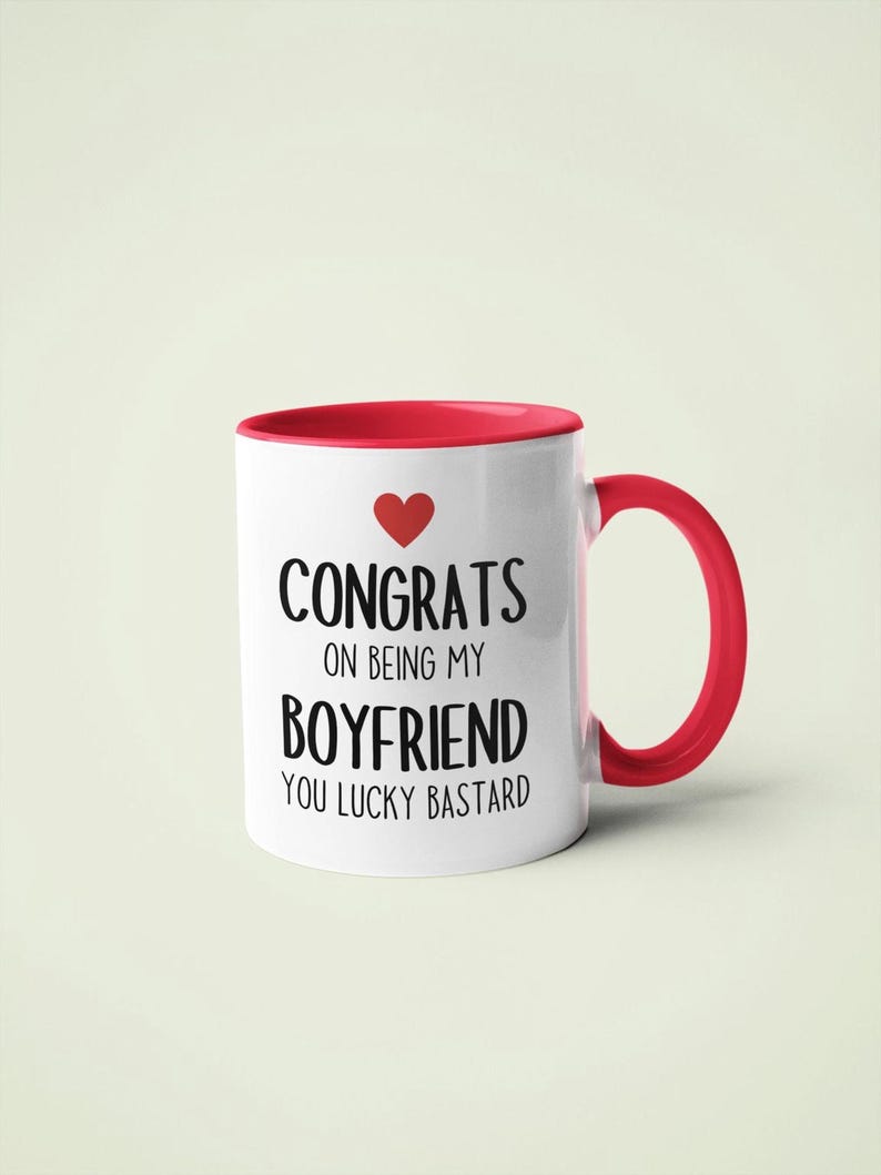 A white and red mug with text that reads "CONGRATS ON BEING MY BOYFRIEND YOU LUCKY BASTARD" printed on it.