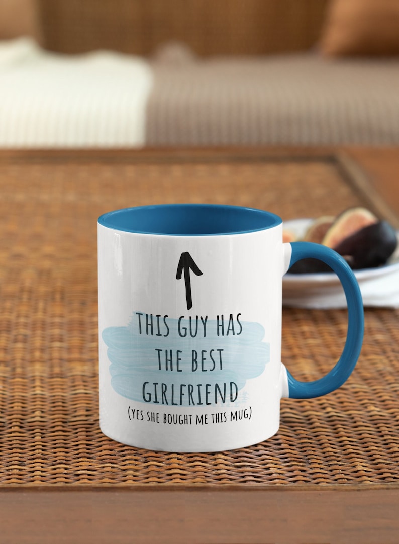 Pode incluir: Caneca de cer&acirc;mica branca com borda e al&ccedil;a azuis. A caneca tem um design de aquarela azul e texto preto que diz "Este cara tem a melhor namorada (sim, ela me comprou esta caneca)".