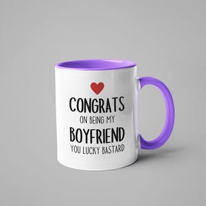 A white and purple mug with text that reads "CONGRATS ON BEING MY BOYFRIEND YOU LUCKY BASTARD" printed on it.