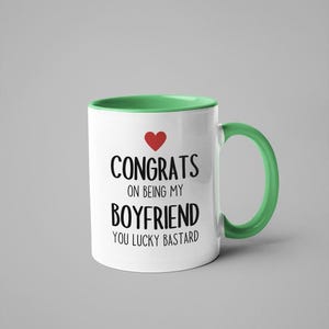 A white and green mug with text printed on it.