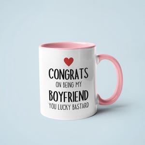 A white and pink mug with text printed on it.