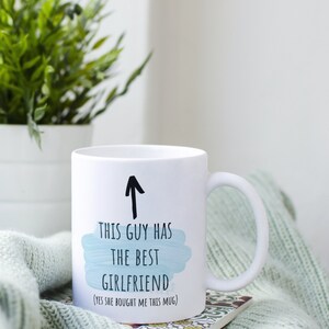 Pode incluir: Caneca de cer&acirc;mica branca com uma seta preta apontando para cima e o texto "Este cara tem a melhor namorada (sim, ela me comprou esta caneca)".