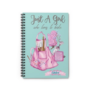 May include: A teal blue spiral bound notebook with the text "Just A Girl who loves to bake" in gray script. The notebook features a pink apron with baking tools and the name "Chloe" in a pink banner.