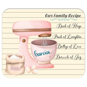 May include: A pink stand mixer with a brown bowl and a bag of flour. The mixer has the word "Garcia" written on the bowl. The text "Our Family Recipe" is at the top of the image, with a list of ingredients: "Dash of Hugs", "Pinch of Laughter", "Dollop of Love", and "Drizzle of Joy".