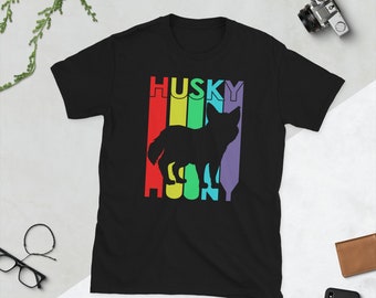 Op de afbeelding: Zwart T-shirt met een regenboogkleurig vintage ontwerp met een husky-silhouet en het woord "HUSKY" in wit.