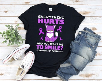May include: Black t-shirt with a purple cat and the text "EVERYTHING HURTS AND YOU WANT ME TO SMILE? FIBROMYALGIA AWARENESS". The cat has a white chest and is surrounded by purple awareness ribbons.