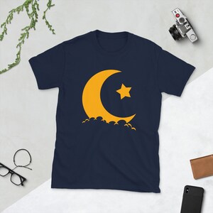 May include: A navy blue t-shirt with a yellow crescent moon and star graphic.