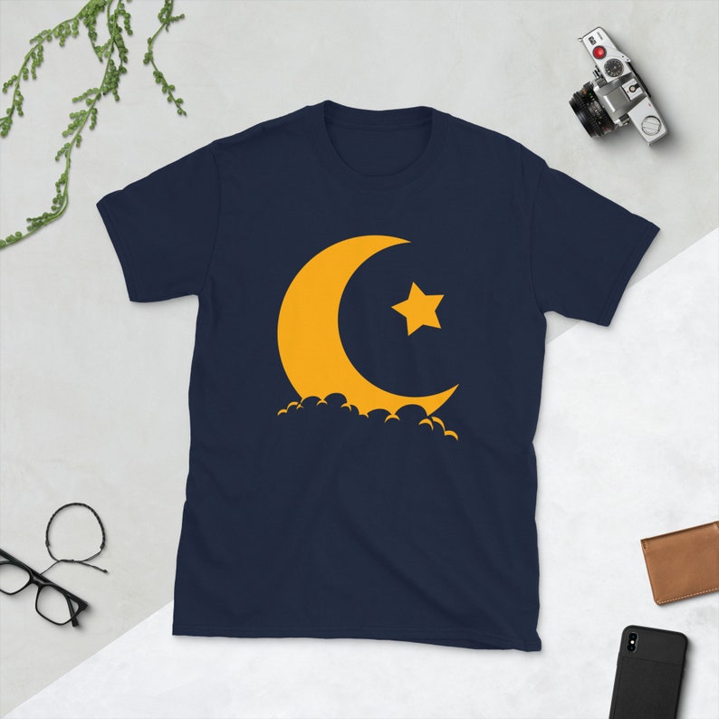 May include: A navy blue t-shirt with a yellow crescent moon and star graphic.