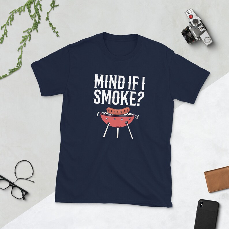 May include: Navy blue t-shirt with white text that reads "Mind if I smoke?" and a cartoon image of a grill with a sausage on it.
