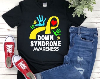 Op de afbeelding: Zwart T-shirt met een geel lint, een rood hart en kleurrijke handafdrukken. De tekst "Down Syndrome Awareness" is op het T-shirt gedrukt.