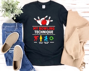 May include: Black t-shirt with a bowling ball graphic and the text "My Bowling Technique". The graphic shows a bowling ball and pins with the text "Bowl", "Yell at 10 Pin", "Pray for Spare", and "Repeat".