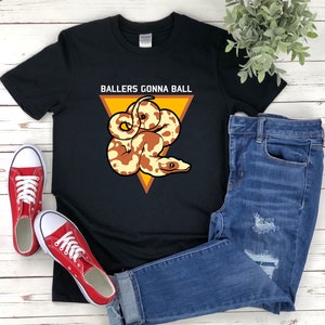 Op de afbeelding: Zwart T-shirt met een afbeelding van een slang in een driehoek met de tekst "Ballers Gonna Ball" erop gedrukt.