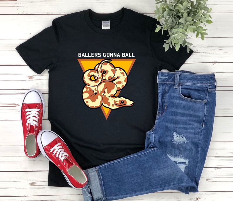 Op de afbeelding: Zwart T-shirt met een afbeelding van een slang in een driehoek met de tekst "Ballers Gonna Ball" erop gedrukt.