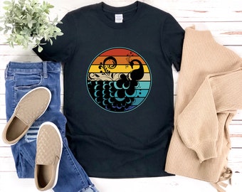 May include: Black t-shirt with a vintage-style graphic of a peacock with a colorful sunset background.