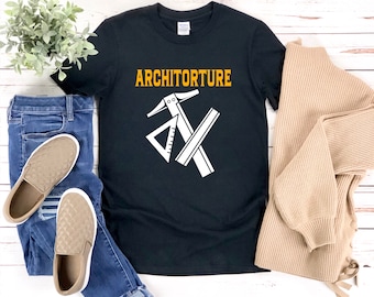 Può includere: Maglietta nera con il testo "Architorture" in lettere gialle e una grafica bianca di strumenti architettonici.