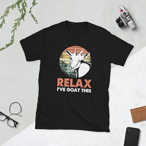 Może przedstawiać: Czarny T-shirt z retro grafiką zachodu słońca przedstawiającą kozę i tekstem "Relax I've Goat This".