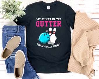 May include: Black t-shirt with a bowling ball and pins graphic. The text on the shirt reads "My mind's in the gutter but my balls aren't".