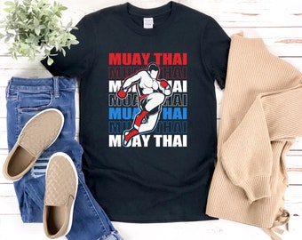May include: Black t-shirt with a graphic of a Muay Thai fighter and the text "MUAY THAI" repeated in red, blue, and white.